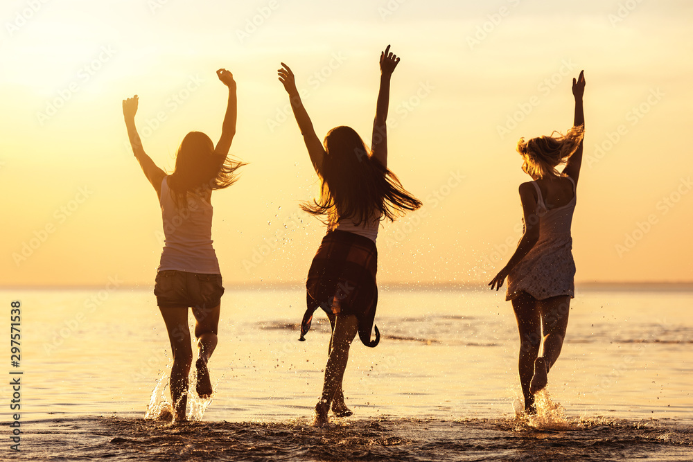 Three happy girls at caml sea beach and sunset - obrazy, fototapety, plakaty 