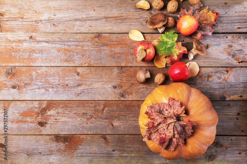 Orange pumpkin with cardoncelli mashrooms, apples, walnuts and colorful leaves on old rustic wooden boards. Autumn Thanksgiving day background