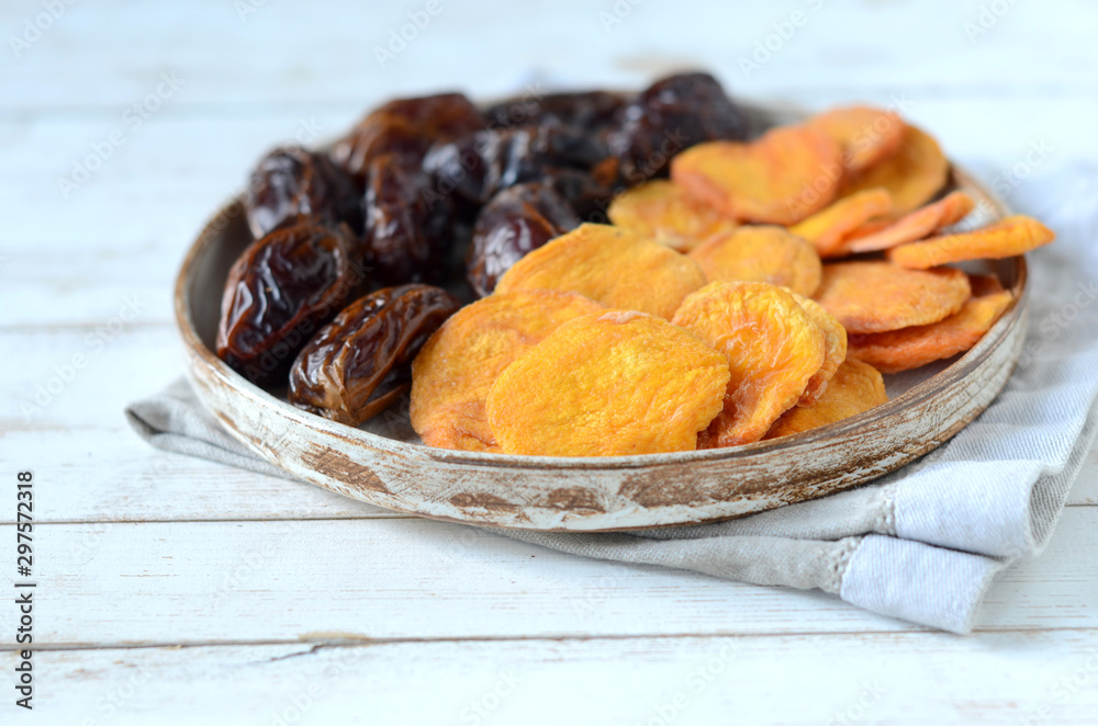 Fototapeta premium Dried dates and dried apricots on a white wooden background