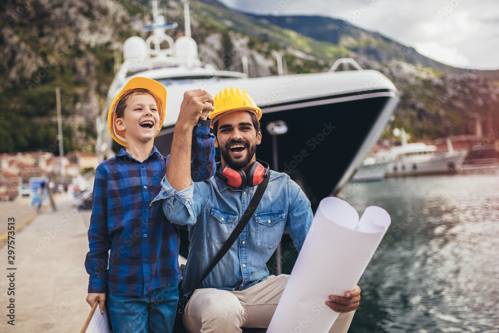 Harbor engineer with his son holding the paper, construction work, smiling.