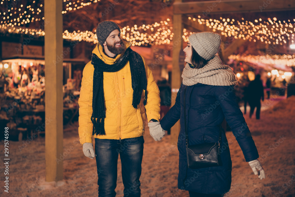 Obraz premium Photo of two adorable people guy lady walking lights midnight gifts market newyear evening enjoy snowy weather wear winter coats scarfs hats gloves outdoors
