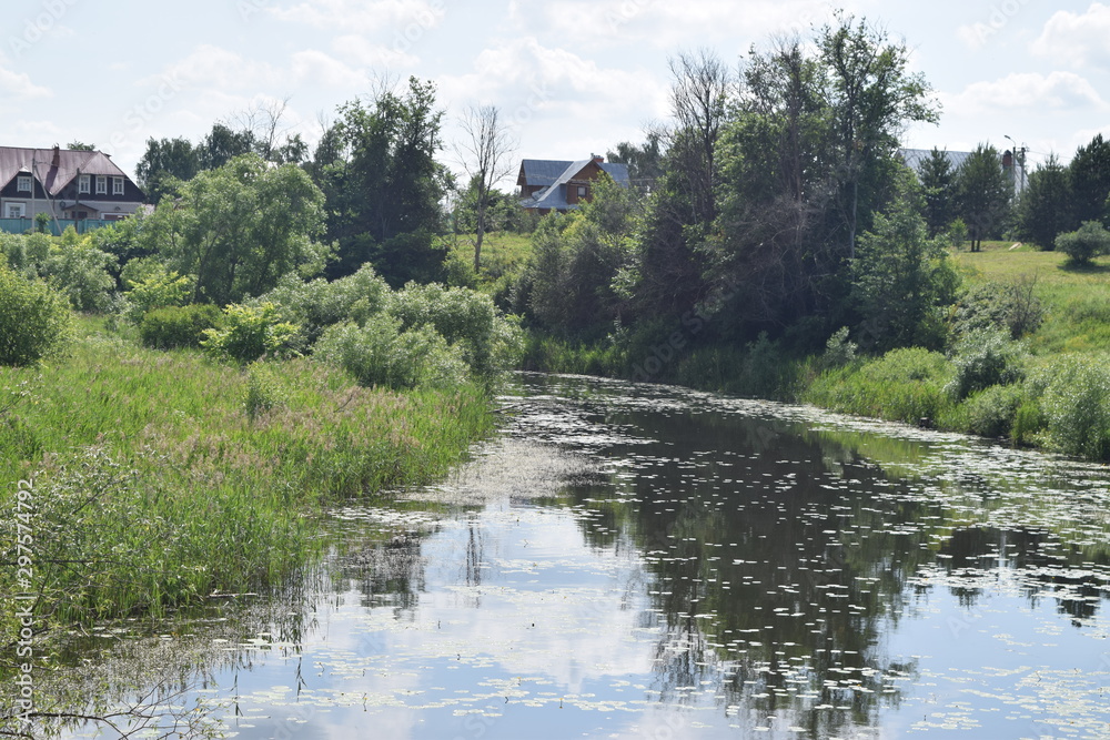 A small river with a calm flow surrounded by trees. Russian landscape. Suzdal, Russia. A small river with a calm flow surrounded by trees. Russian landscape. Suzdal, Russia.
