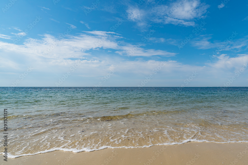 gentle waves on an empty sandy beach with a calm ocean