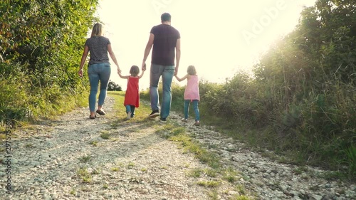 Father and mother walk hand in hand with their two daughters