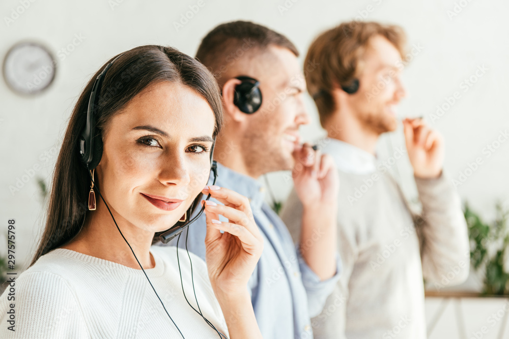 selective focus of attractive broker touching headset near men in office selective focus of attractive broker touching headset near men in office