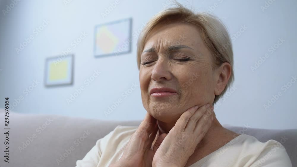 Elderly woman touching painful throat, angina problem, seasonal sickness Elderly woman touching painful throat, angina problem, seasonal sickness