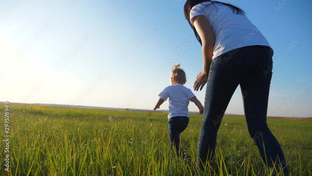 A young mother plays with a child on the street. A woman runs after a little cheerful daughter. Happy family having fun outdoors. A young mother plays with a child on the street. A woman runs after a little cheerful daughter. Happy family having fun outdoors.
