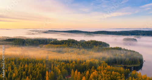 Aerial view of Pulkkilanharju Ridge, Paijanne National Park, southern part of Lake Paijanne. Landscape with drone. Fields, houses and orange forests from above on a sunrise autumn day in Finland.
