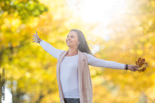 Happiness woman in autumn park holding bouquet with fall leaves