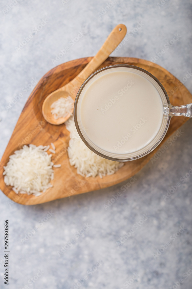 The concept of a vegetarian diet. Rice milk in the glass with rice grains . Light background The concept of a vegetarian diet. Rice milk in the glass with rice grains . Light background