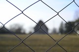 fence in the focus with a house and the field behind
