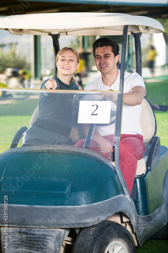 Male and female golf partners using golf cart
