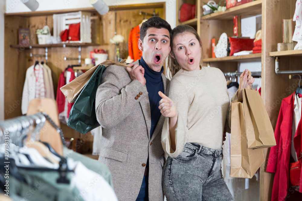 Smiling couple is satisfied of purchases and standing with package