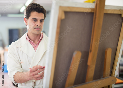 Man near easel painting on canvas