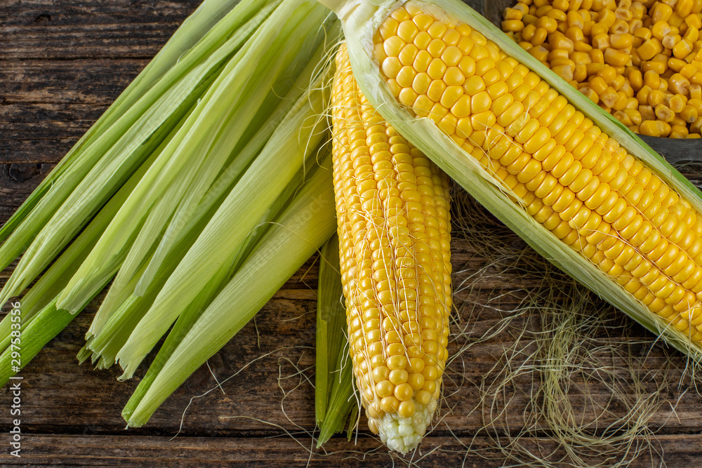 Corns on the wooden rustic table with their cobs Corns on the wooden rustic table with their cobs