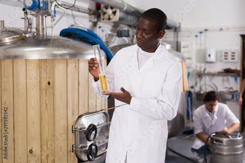 African american man expert with flask for beer and analizying photo