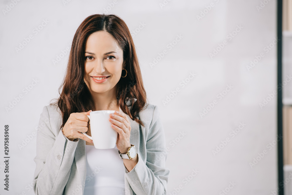 attractive, young secretary looking at camera while holding coffee cup attractive, young secretary looking at camera while holding coffee cup