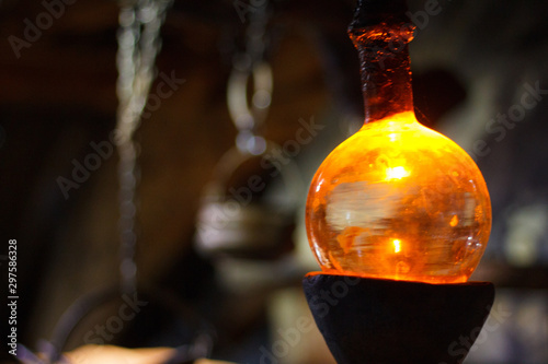 Alchemy test tube in laboratory of alchemist. Orange old glass pot.   Alchemy symbol and objects. 