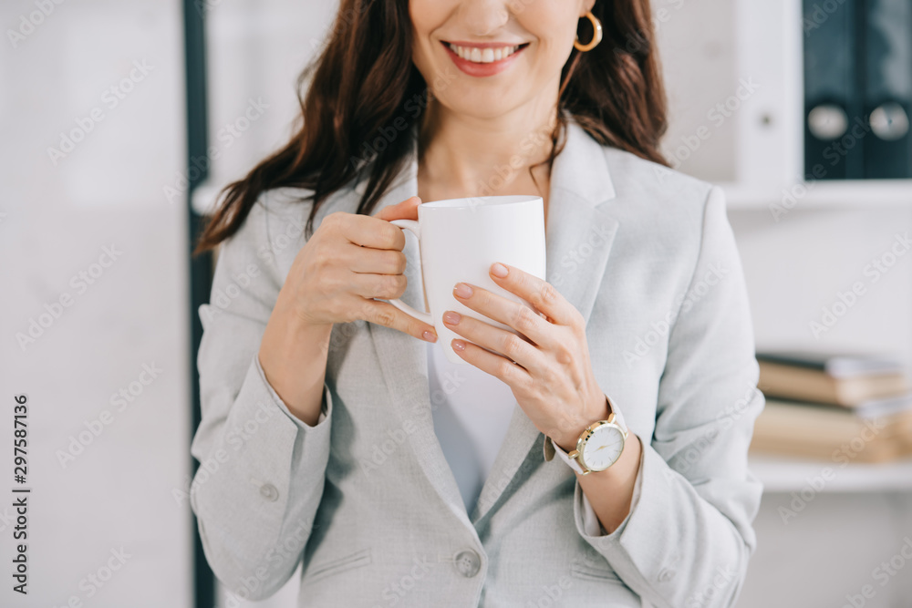 cropped view of smiling secretary holding coffee cup in office cropped view of smiling secretary holding coffee cup in office