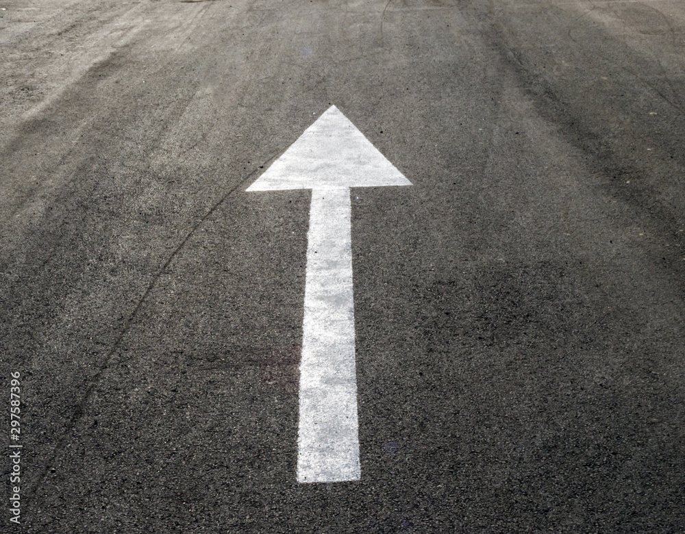 Arrow on the pavement directed from us. The theme of signs and symbols surrounding us Arrow on the pavement directed from us. The theme of signs and symbols surrounding us