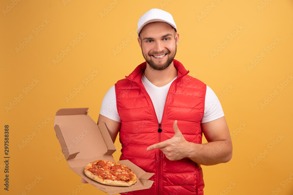 A Man With A Piece Of Pizza In His Hands Poses On The Camera. Man Sitting  At A Table Near The Pizza Box Looking At The Camera. Stock Photo, Picture  and Royalty