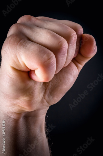 Aggressive gesture. Hand compressed in fist. Photo against dark background