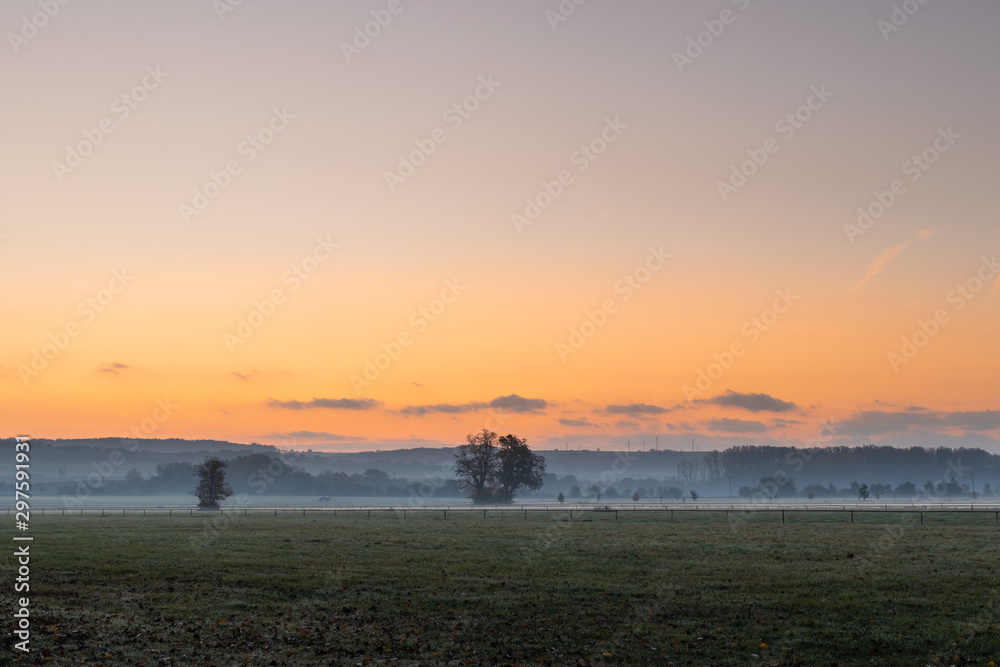 Sunrise over fog at countryside. Tranquil scene at misty morning over pasture