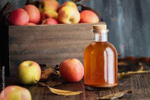 Fototapeta Naklejka Na Ścianę i Meble -  Apple cider vinegar with the mother, yeast and healthy bacteria, surrounded by fresh apples. Apple cider vinegar has long been used in naturopathy to treat things such as diabetes and high cholesterol
