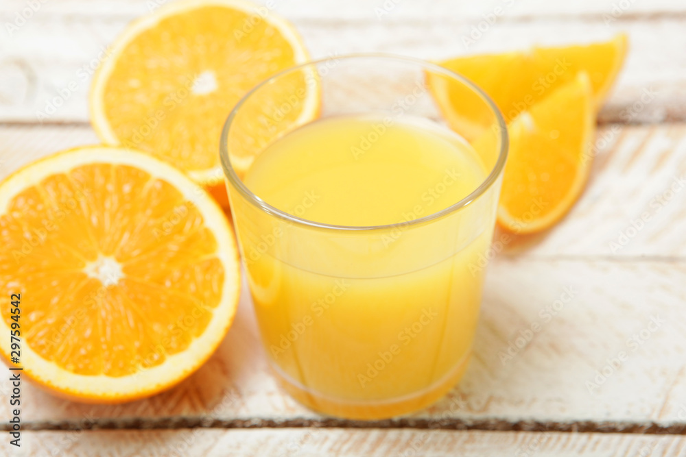 Orange juice in a glass, oranges and orange slices on the table.