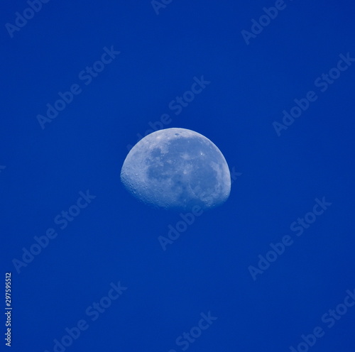 Image of a three quarter moon in front of a blue sky