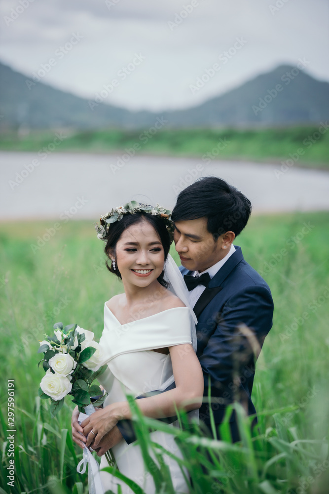 Wedding photo outdoor, Newlyweds are hugging each other happily in the middle of the green fields on the morning of the wedding day. Wedding photo outdoor, Newlyweds are hugging each other happily in the middle of the green fields on the morning of the wedding day.