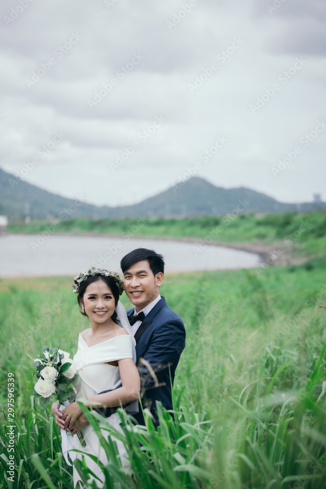 Wedding photo outdoor, Newlyweds are hugging each other happily in the middle of the green fields on the morning of the wedding day. Wedding photo outdoor, Newlyweds are hugging each other happily in the middle of the green fields on the morning of the wedding day.