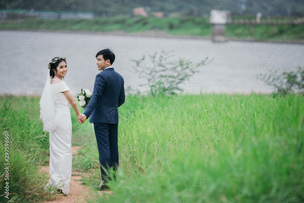 Couples in romantic wedding dresses are enjoying a stroll through the beautiful sunset with a green grass background. Couples in romantic wedding dresses are enjoying a stroll through the beautiful sunset with a green grass background.