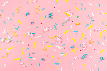 Colorful paper confetti exploding on pastel pink background