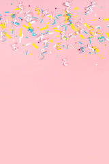 Colorful paper confetti exploding on pastel pink background