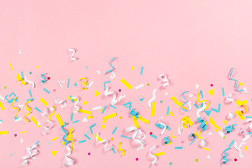 Colorful paper confetti exploding on pastel pink background
