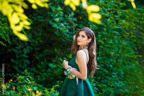 Beautiful brunette girl in glamorous green dress in nature. Ready for prom night photo