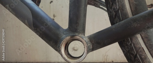 Looking through the bottom bracket shell of a biciycle frame at the concrete wall behind with a little unfocused snail climbing on it photo