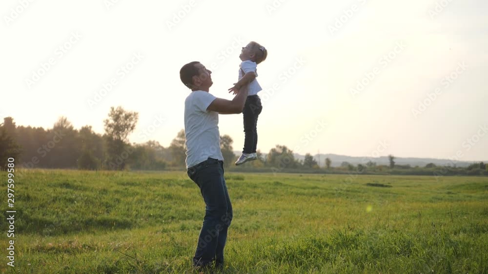 Carefree happy family enjoying a day off in the fresh air. Dad holds a little happy cute daughter in his arms while playing together in nature in the countryside. Carefree happy family enjoying a day off in the fresh air. Dad holds a little happy cute daughter in his arms while playing together in nature in the countryside.