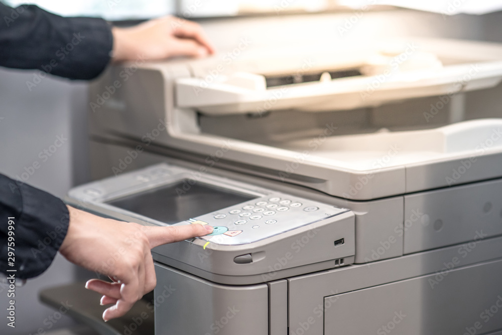 Male hand pushing button on photocopier copying and printing report paperwork in office. Electronic equipment and supply for business organization. Male hand pushing button on photocopier copying and printing report paperwork in office. Electronic equipment and supply for business organization.