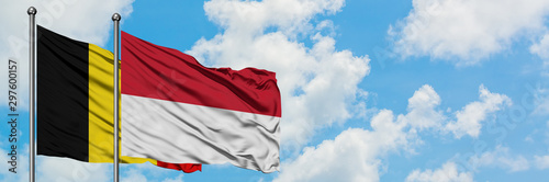 Belgium and Indonesia flag waving in the wind against white cloudy blue sky together. Diplomacy concept, international relations.