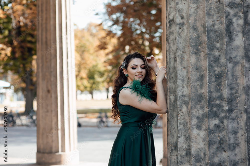 Portrait of beautiful young girl in green dress. Fashion photo. Beautiful long curly hair woman with closed makeup eyes and manicured nails. Young beautiful stylish girl walking and posing. 