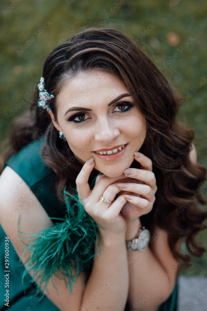 Naklejka premium Beauty fashion portrait. Sexy face of an attractive lady posing. Attractive young girl touching hands face. Photo girl with perfect skin ourdoor. Beautiful woman with long brown curly hair. 