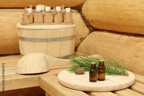 Bottles with healing essential oil for sauna near green pine branch. The concept of natural aromatherapy and spa treatment.