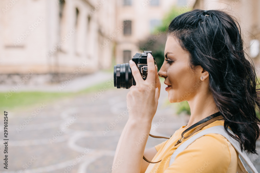 side view of attractive girl holding digital camera while taking photo