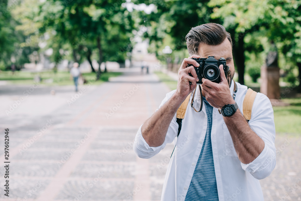 man covering face while taking photo on digital camera