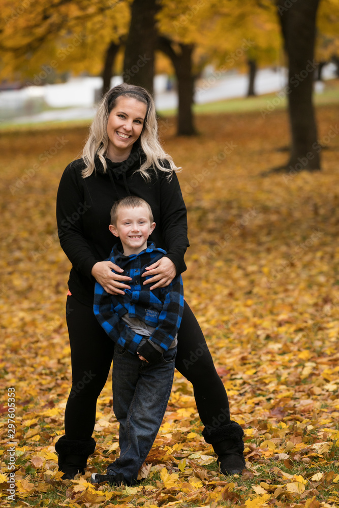Fototapeta premium Cute young mother and son posing for portrait in autumn color