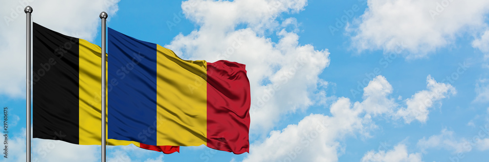 Obraz premium Belgium and Romania flag waving in the wind against white cloudy blue sky together. Diplomacy concept, international relations.
