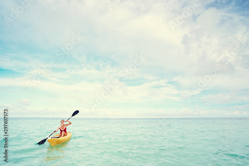 Young woman paddling the sea kayak in thel calm lagoon.