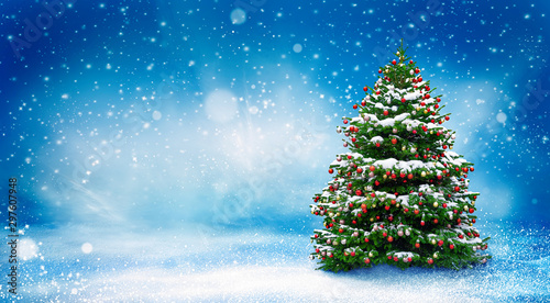 Beautiful Christmas snowy background. Christmas tree decorated with red balls in snowfall. Winter landscape.